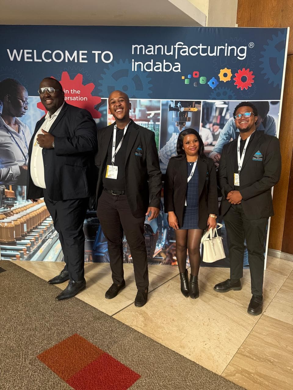 Team members photographed at a manufacturing industry event display