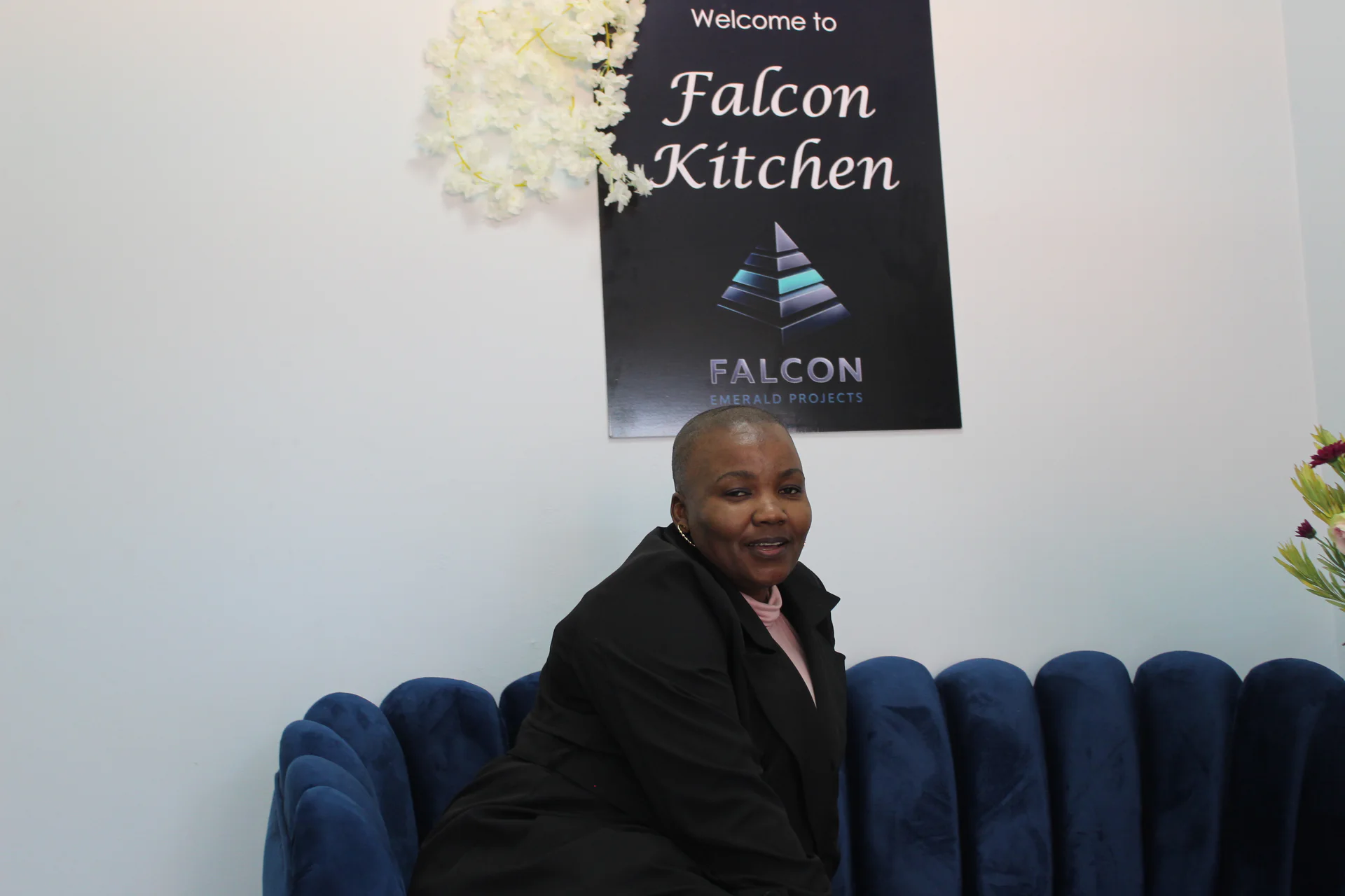 Falcon Kitchen team member seated below branded Falcon Kitchen signage