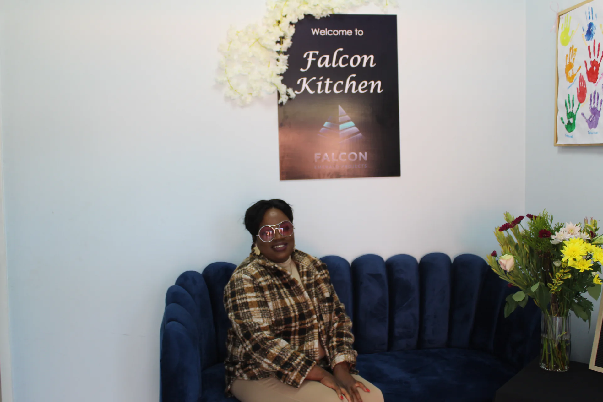 Team member seated in the Falcon Kitchen service area with signage and floral decor