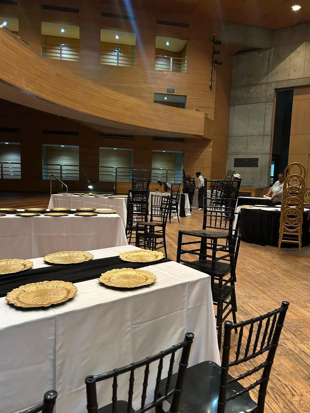 Event dining tables arranged with black and white linen and gold charger plates